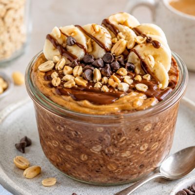 High-protein peanut butter chocolate overnight oats topped with banana, peanuts and chocolate chips
